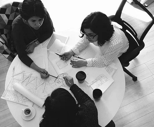 Echelle humaine architecture - image noir et blanc vue de haut de trois femmes architectes en pleine discussion avec des plans